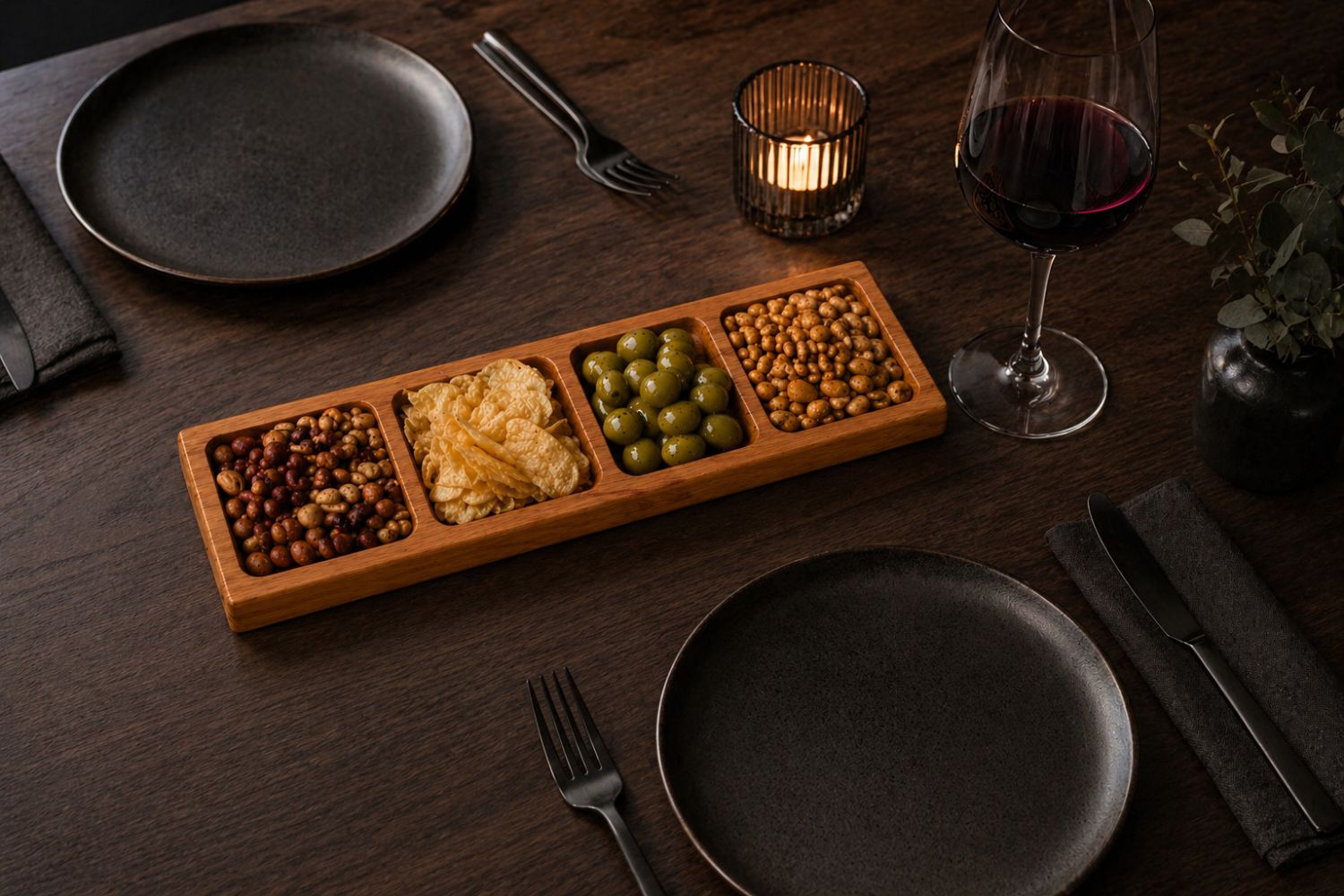 Servierbrett aus Holz mit 4 Fächern gefüllt mit Snacks auf einem modern gedeckten Tisch